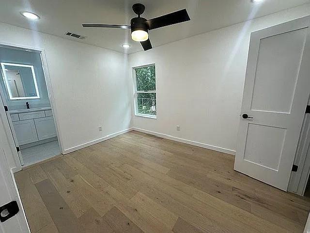unfurnished bedroom with wood finished floors, baseboards, ensuite bath, visible vents, and recessed lighting