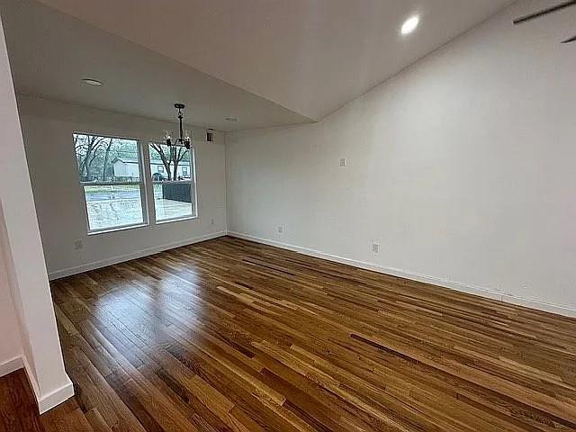 unfurnished dining area with recessed lighting, baseboards, an inviting chandelier, and dark wood-type flooring
