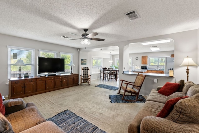 living area with visible vents, arched walkways, and ceiling fan