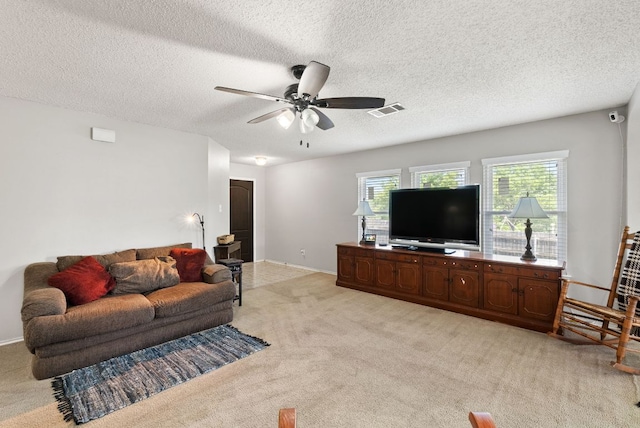 living room featuring visible vents, a textured ceiling, ceiling fan, and light carpet