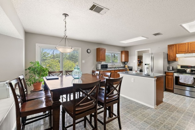 dining room featuring light floors, a textured ceiling, and visible vents