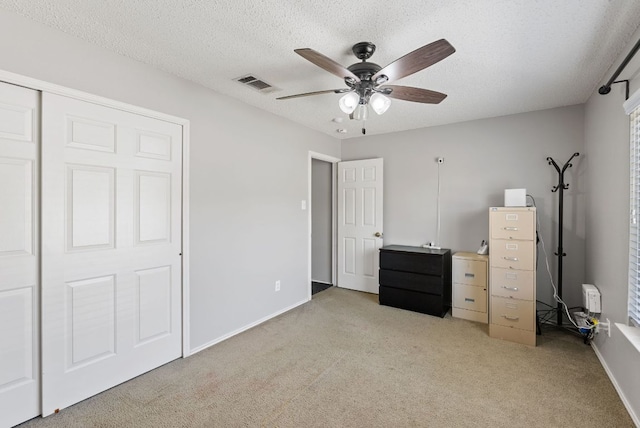 unfurnished bedroom with baseboards, light colored carpet, a textured ceiling, and visible vents
