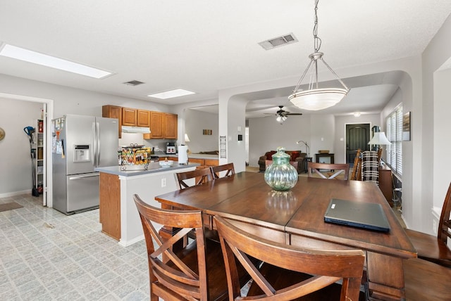 dining room featuring visible vents, arched walkways, light floors, and ceiling fan