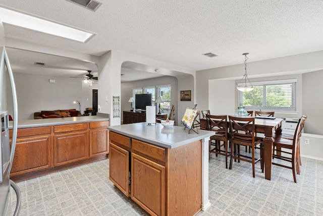 kitchen with visible vents, a textured ceiling, and brown cabinets