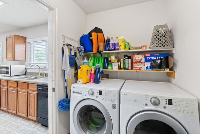 clothes washing area with laundry area, washer and clothes dryer, a sink, and a textured ceiling