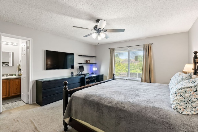 bedroom with ceiling fan, light colored carpet, a sink, ensuite bath, and a textured ceiling