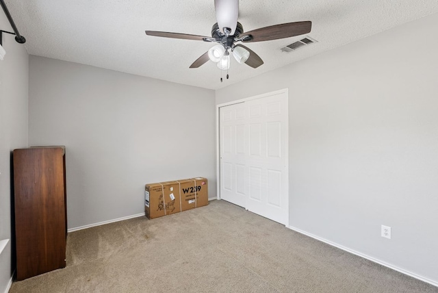 unfurnished bedroom with carpet floors, a textured ceiling, a ceiling fan, baseboards, and visible vents