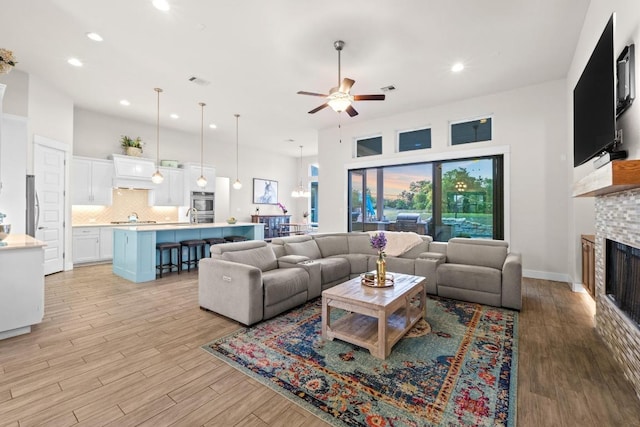 224 Highland Oaks, Leander, TX 78641 - living room with a ceiling fan, a fireplace, recessed lighting, light wood finished floors, and a towering ceiling