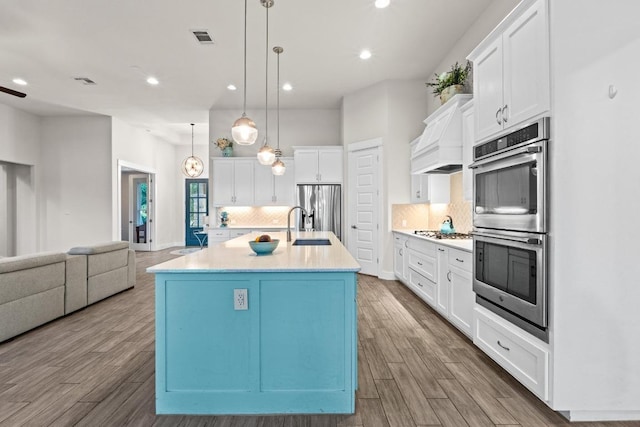 224 Highland Oaks, Leander, TX 78641 - kitchen with stainless steel appliances, wood finished floors, white cabinets, decorative backsplash, and recessed lighting