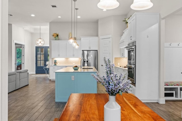 224 Highland Oaks, Leander, TX 78641 - kitchen with appliances with stainless steel finishes, wood finished floors, a kitchen island with sink, tasteful backsplash, and white cabinets
