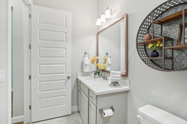 half bath featuring baseboards, toilet, and vanity