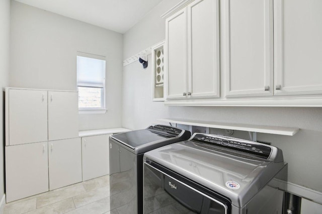 laundry area featuring light tile patterned floors, cabinet space, and washer and clothes dryer