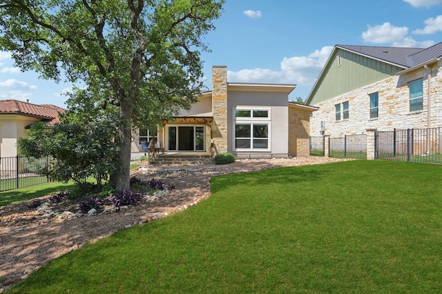 back of house featuring a lawn, fence, and stone siding