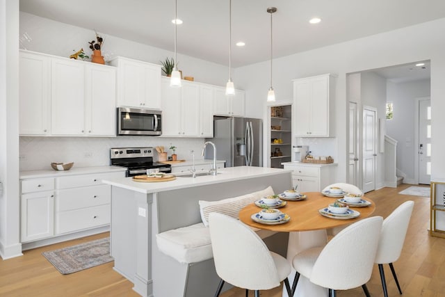 17508 Emperador Dr Unit 65, Pflugerville, TX 78664 - kitchen with appliances with stainless steel finishes, a sink, backsplash, light wood-style flooring, and a kitchen island with sink