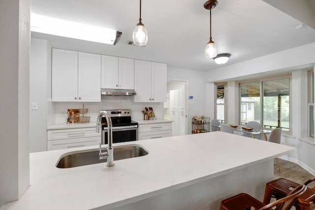 402 San Gabriel Blvd, Georgetown, TX 78628 - kitchen featuring under cabinet range hood, stainless steel electric stove, a sink, backsplash, and a kitchen bar