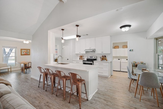 402 San Gabriel Blvd, Georgetown, TX 78628 - kitchen with stainless steel electric stove, independent washer and dryer, a sink, under cabinet range hood, and a kitchen bar