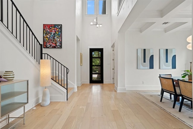 entrance foyer with wood finished floors, stairs, beamed ceiling, baseboards, and visible vents