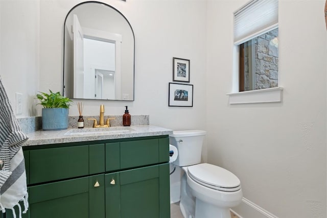bathroom featuring toilet, vanity, and baseboards