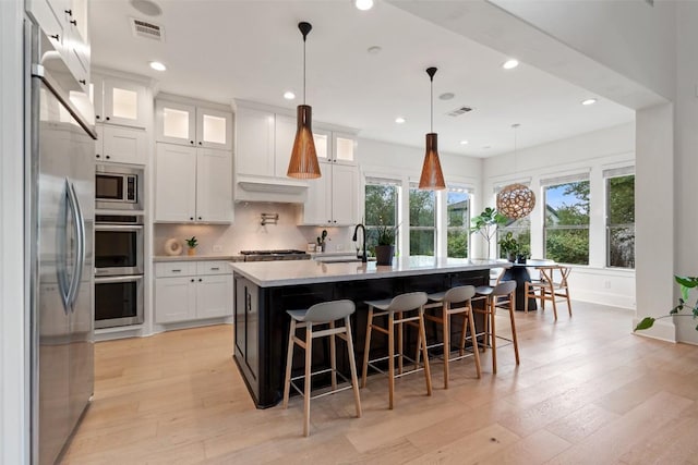 kitchen with light countertops, a sink, plenty of natural light, and built in appliances