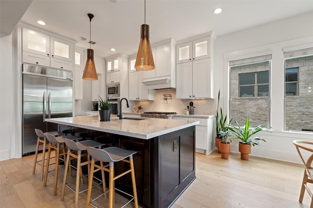 710 Crestone Stream Dr, Austin, TX 78738 - kitchen featuring built in appliances, light wood-type flooring, a center island with sink, light stone counters, and recessed lighting