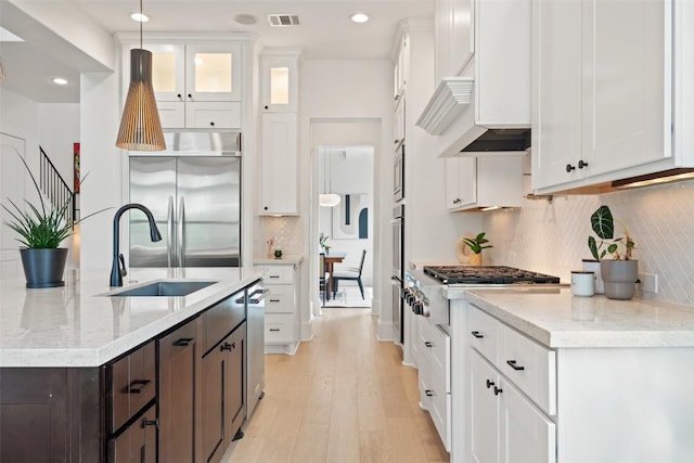 710 Crestone Stream Dr, Austin, TX 78738 - kitchen featuring appliances with stainless steel finishes, dark brown cabinets, white cabinets, a center island with sink, and recessed lighting