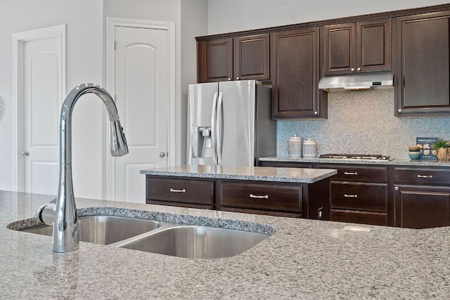200 S Sage Holw, Dripping Springs, TX 78620 - kitchen with appliances with stainless steel finishes, under cabinet range hood, dark brown cabinetry, and light stone counters