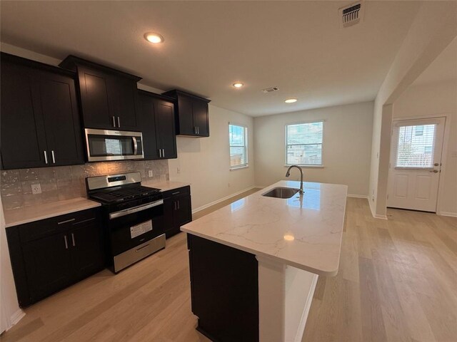 577 Backstays Loop, Kyle, TX 78640 - kitchen with appliances with stainless steel finishes, dark cabinets, backsplash, light wood-style flooring, and recessed lighting