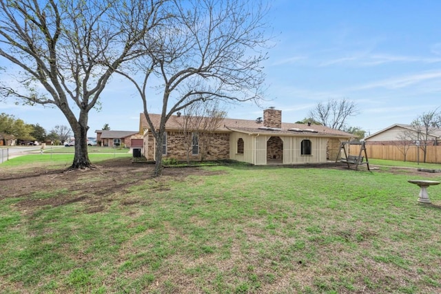 back of property featuring fence, a lawn, a chimney, and board and batten siding