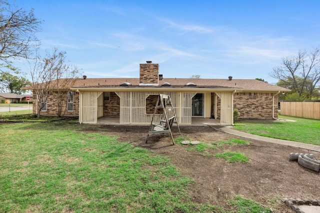 rear view of house featuring a patio area, a lawn, a chimney, and fence