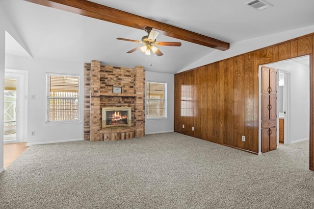 unfurnished living room featuring light carpet, vaulted ceiling with beams, visible vents, a brick fireplace, and ceiling fan