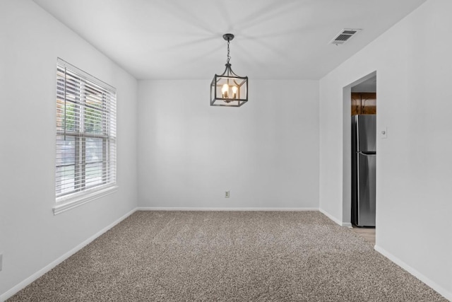 empty room with light colored carpet, baseboards, a chandelier, and visible vents