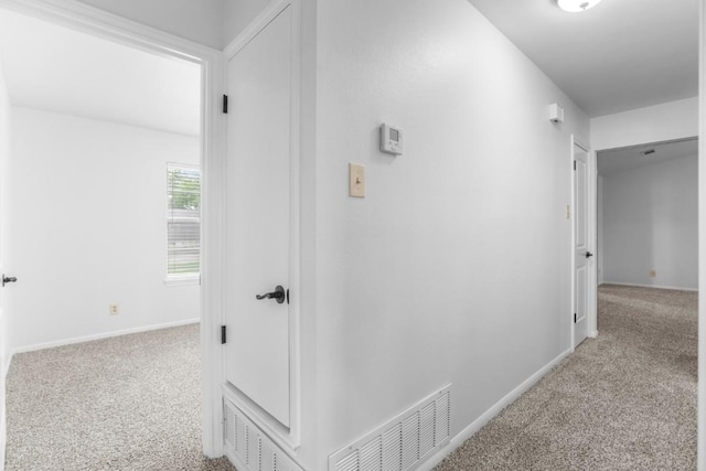 hall with visible vents, carpet flooring, and baseboards