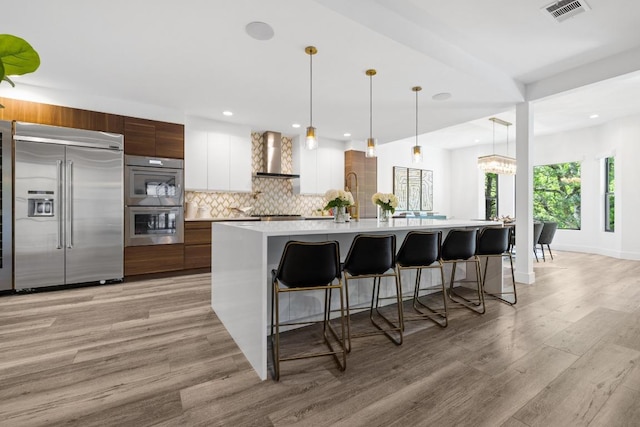6103 Twin Ledge Dr, Austin, TX 78731 - kitchen featuring appliances with stainless steel finishes, wall chimney exhaust hood, modern cabinets, light countertops, and tasteful backsplash