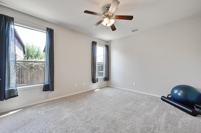 carpeted spare room with ceiling fan, baseboards, and visible vents