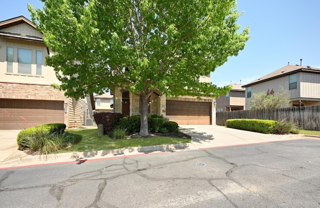 obstructed view of property featuring brick siding, fence, concrete driveway, and a garage