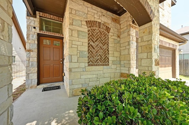 view of exterior entry with stone siding and a garage