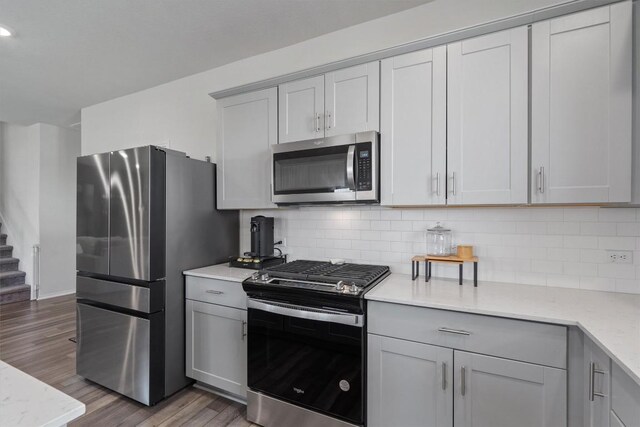145 Fiery Skipper Ln, Georgetown, TX 78626 - kitchen with appliances with stainless steel finishes, wood finished floors, gray cabinets, backsplash, and recessed lighting