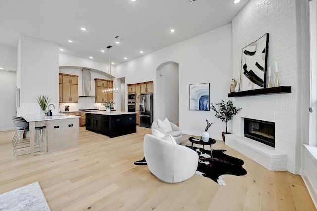 422 Quiet Oak Rd, San Marcos, TX 78666 - living room with light wood-type flooring, a brick fireplace, arched walkways, and recessed lighting
