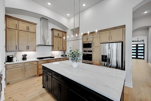 422 Quiet Oak Rd, San Marcos, TX 78666 - kitchen with stainless steel appliances, wall chimney range hood, arched walkways, light wood-type flooring, and a kitchen island