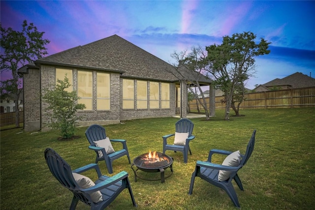 422 Quiet Oak Rd, San Marcos, TX 78666 - back of property at dusk with a fire pit, a lawn, and a fenced backyard