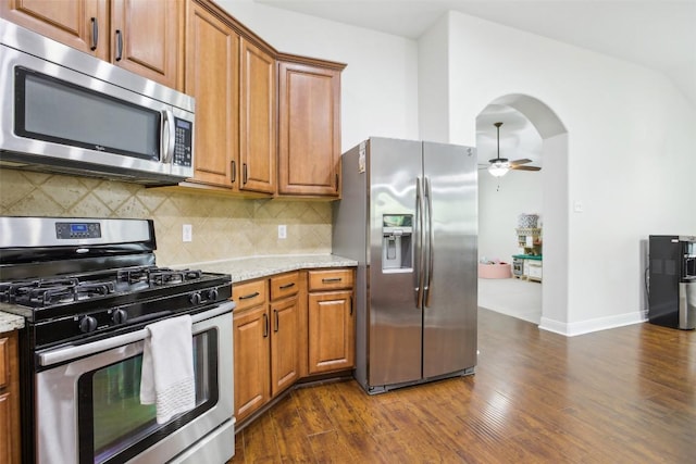 161 Caraway, Kyle, TX 78640 - kitchen with stainless steel appliances, arched walkways, a ceiling fan, and brown cabinetry