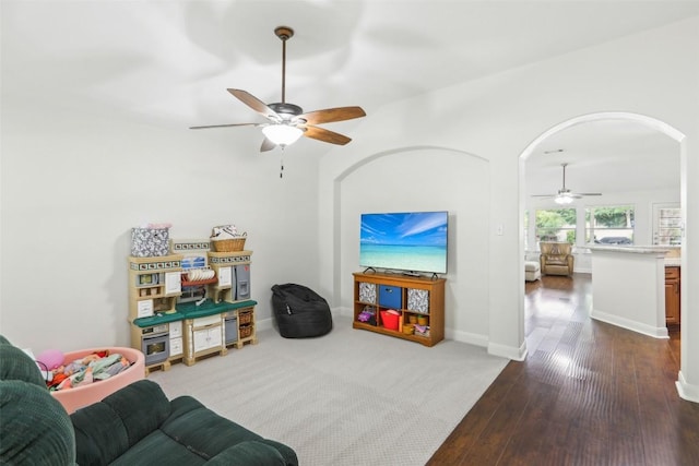 living room featuring a ceiling fan, baseboards, arched walkways, and dark wood-style flooring