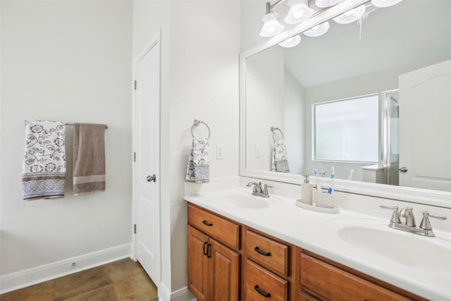 bathroom featuring baseboards, an enclosed shower, a sink, and double vanity