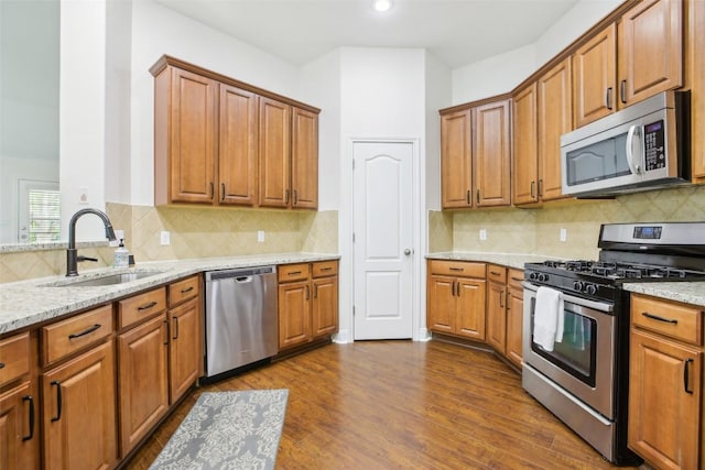 161 Caraway, Kyle, TX 78640 - kitchen featuring stainless steel appliances, a sink, brown cabinets, and light stone countertops