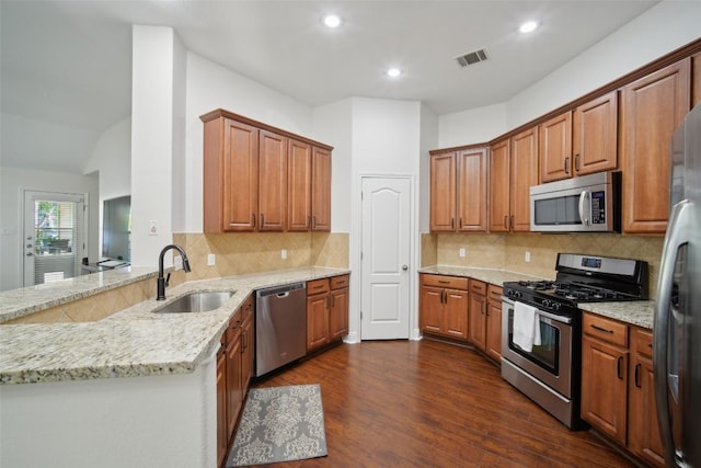 kitchen featuring light stone counters, a sink, appliances with stainless steel finishes, dark wood-style flooring, and visible vents