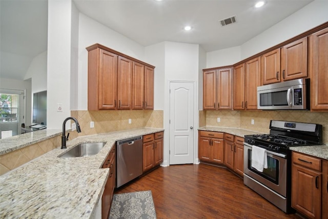 kitchen with light stone counters, a sink, stainless steel appliances, dark wood finished floors, and visible vents