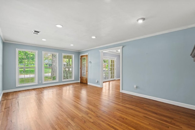 spare room with baseboards, crown molding, visible vents, and a wealth of natural light