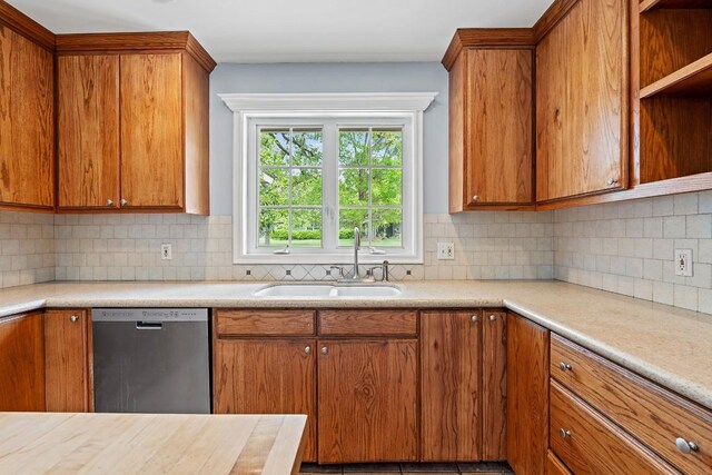 kitchen with a sink, brown cabinets, dishwasher, light countertops, and backsplash