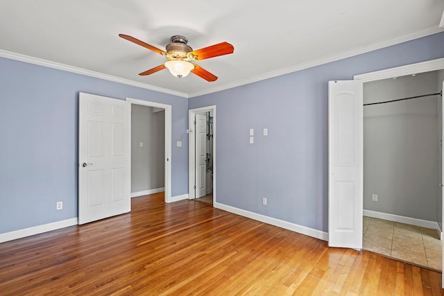 unfurnished bedroom featuring light wood-style flooring, crown molding, baseboards, and a ceiling fan