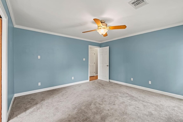 carpeted empty room with baseboards, a ceiling fan, visible vents, and crown molding